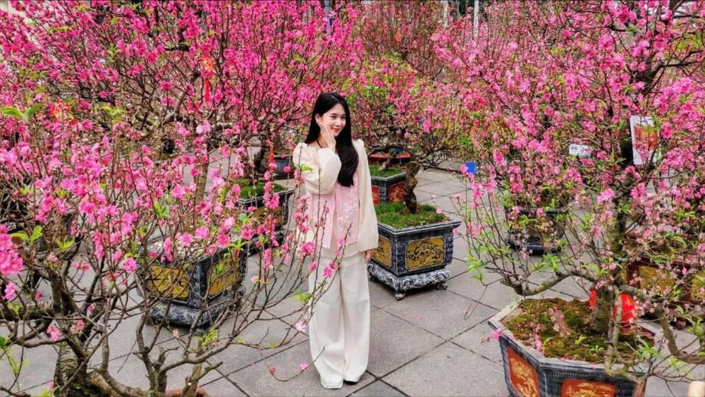 Một bạn trẻ tạo dáng chụp hình bên vườn đào quý ở vườn hoa Lý Thái Tổ. Ảnh: QUỐC KHÁNH