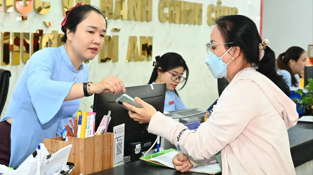 Cán bộ Trung tâm Phục vụ hành chính công phường Dĩ An hướng dẫn người dân đến làm thủ tục hành chính. Ảnh: VIỆT DŨNG