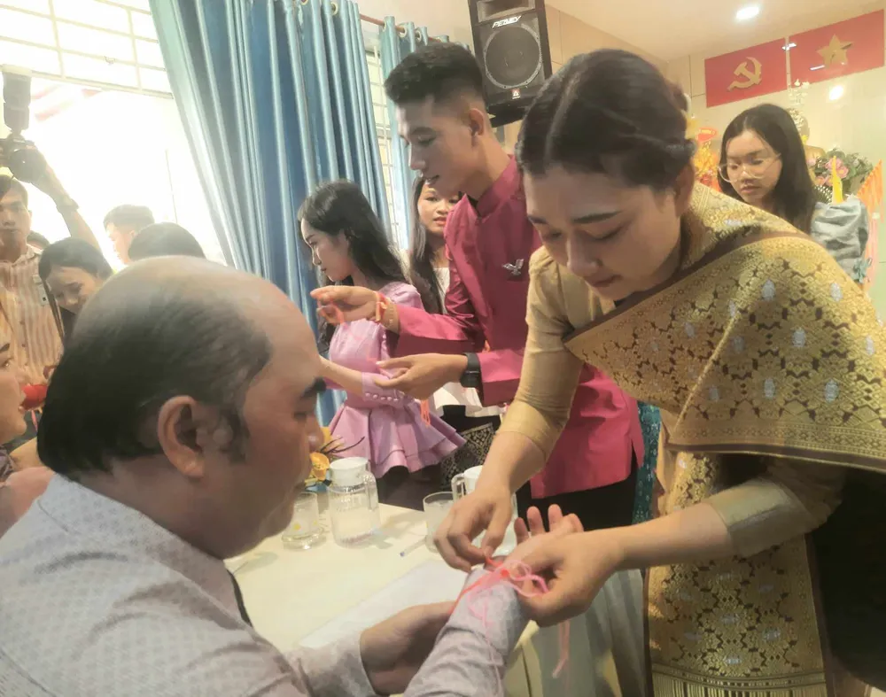 Du học sinh Lào buộc chỉ tay chúc mừng năm mới đến đại biểu dự họp mặt