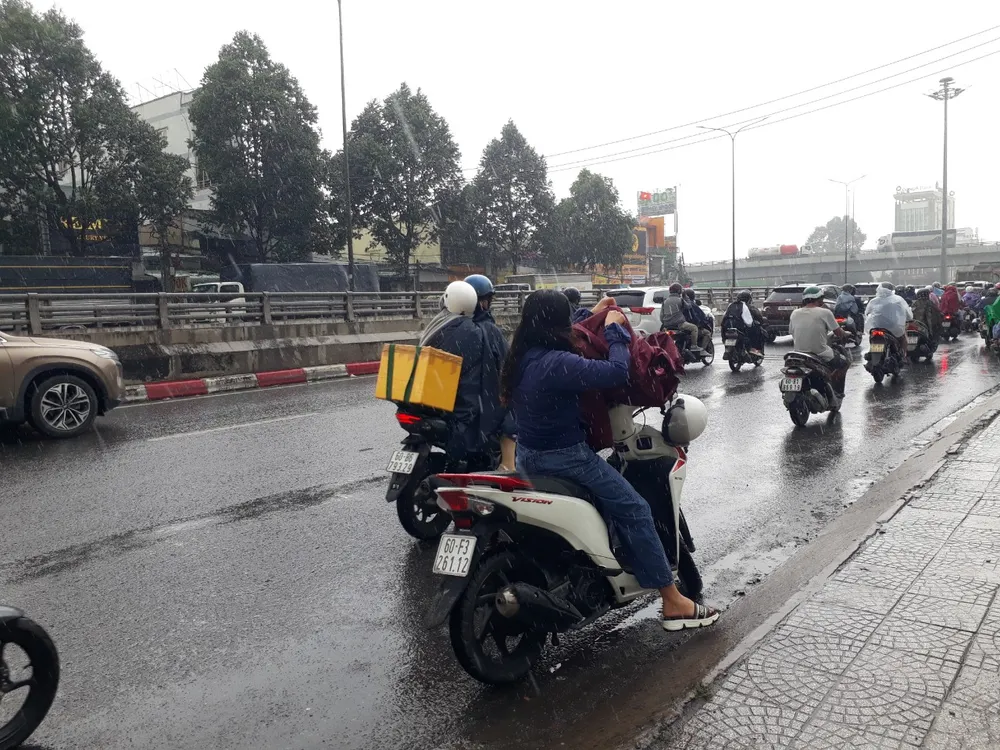 Do trời mưa nên nhiều người phải dừng lại để mặc áo mưa tại Ngã Tư Vũng Tàu (TP Biên Hoà). Ảnh: HOÀNG BẮC