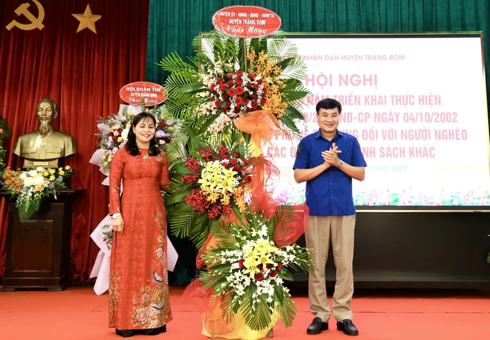 lãnh đạo UBND huyện Trảng Bom (phải) tặng hoa chúc mừng Hội nghị tổng kết 20 năm thực hiện Nghị định số 78 của Chính phủ về tín dụng chính sách trên địa bàn huyện (1).jpg