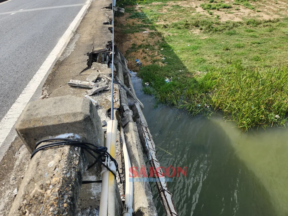 Đoạn lan can trên còn được giữ lơ lững có thể rơi xuống sông bất cứ lúc nào. Ảnh: NGUYỄN CƯỜNG