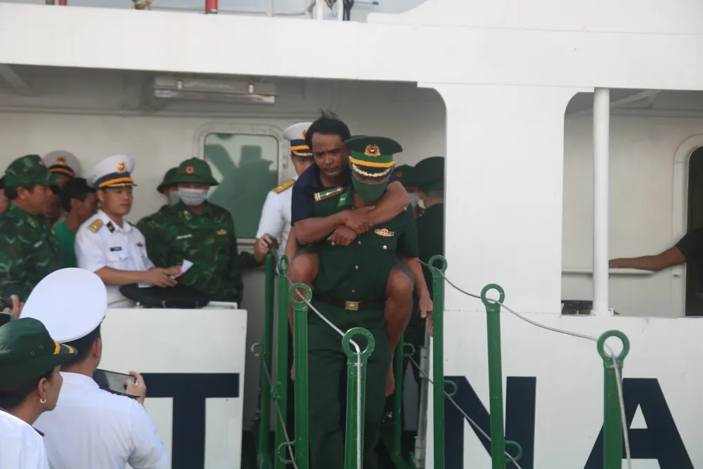 Lực lượng quân đội cõng một ngư dân bị thương từ tàu 467 vào bờ để tiếp tục chữa trị