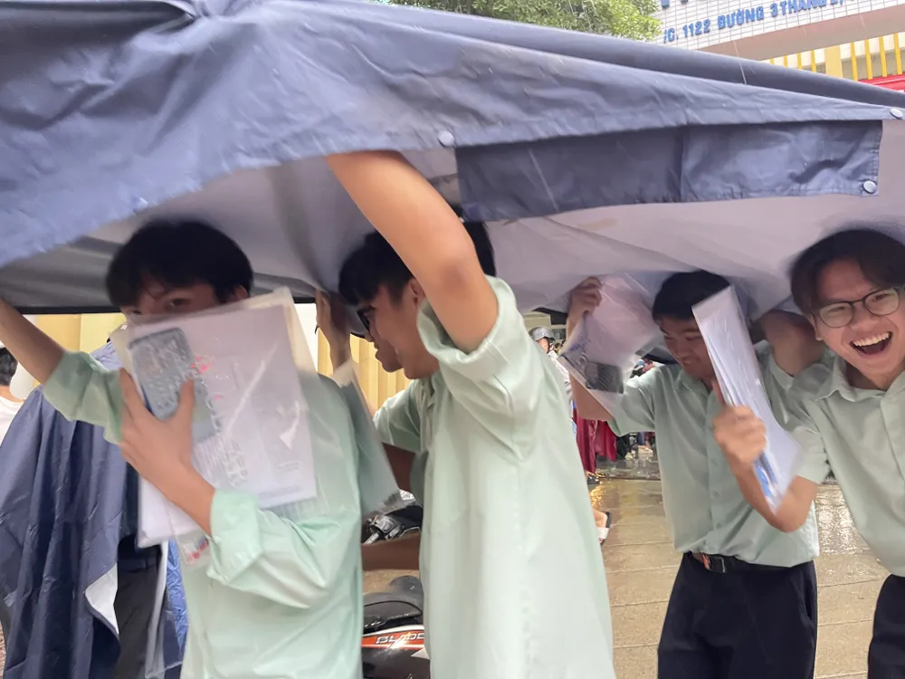 Niềm vui của các thí sinh sau khi hoàn thành môn Toán, tại điểm thi Trường THCS Phú Thọ, quận 11, dưới cơn mưa lớn ngay sau giờ thi. Ảnh: HOÀNG HÙNG