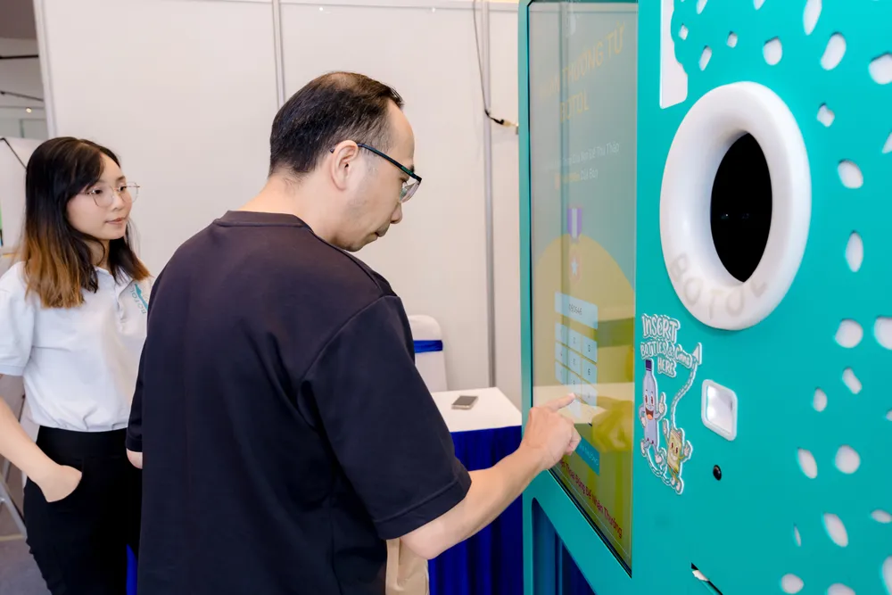 Người dùng trải nghiệm máy thu gom chai nhựa của Liên minh Tái chế Bao bì Việt Nam đặt tại sự kiện.jpg