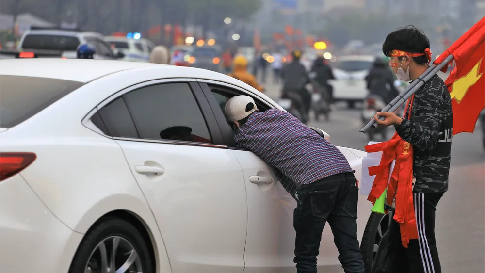 Một phe vé chèo kéo một nhóm người đi ô tô mua vé xem trận đấu
