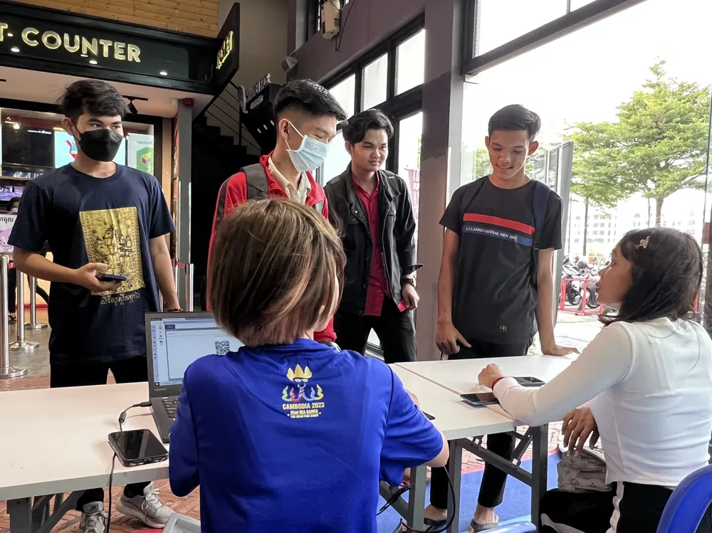 Đại diện Ban tổ chức SEA Games 32 trả vé cho người hâm mộ ở Eden Garden Mall hướng dẫn thủ tục lấy vé. ẢNH: TÂM HÀ