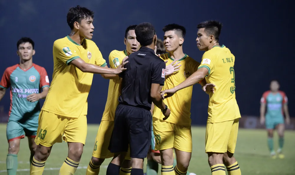 Các cầu thủ Quảng Nam vây lấy trọng tài Trần Văn Khoẻ vì bị thổi phạt đền. ẢNH: DŨNG PHƯƠNG