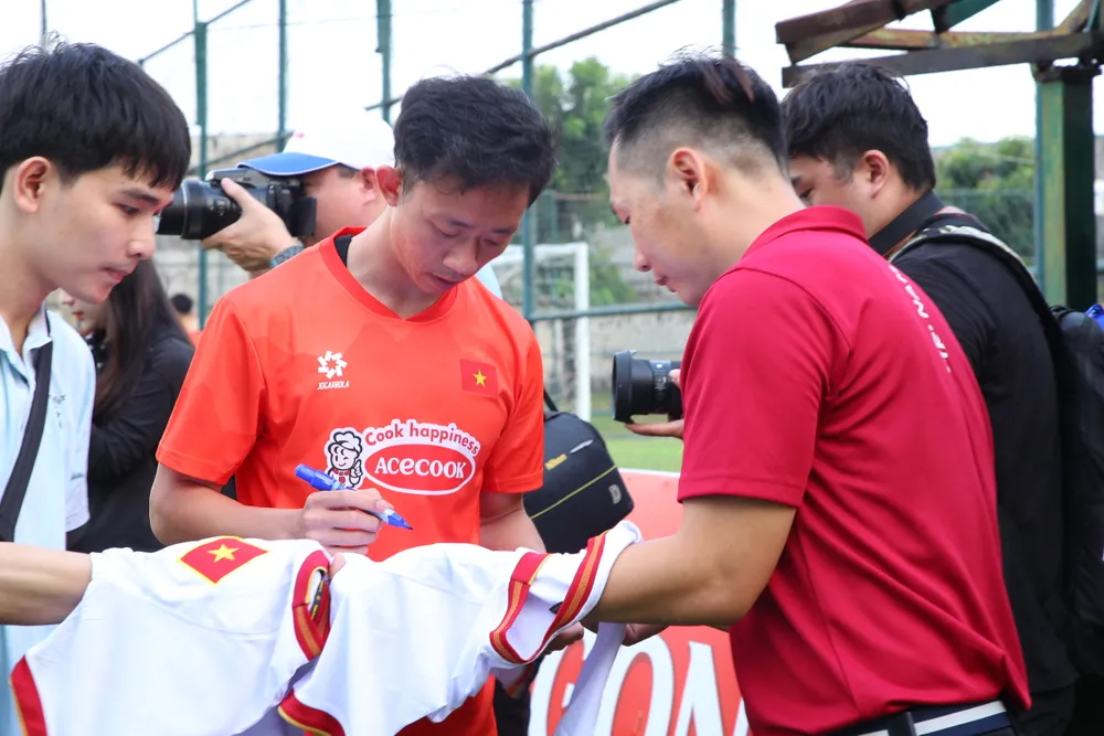 Tiền vệ Châu Ngọc Quang được người hâm mộ vào tận sân tập vây lấy xin chữ ký. ẢNH: DŨNG PHƯƠNG 