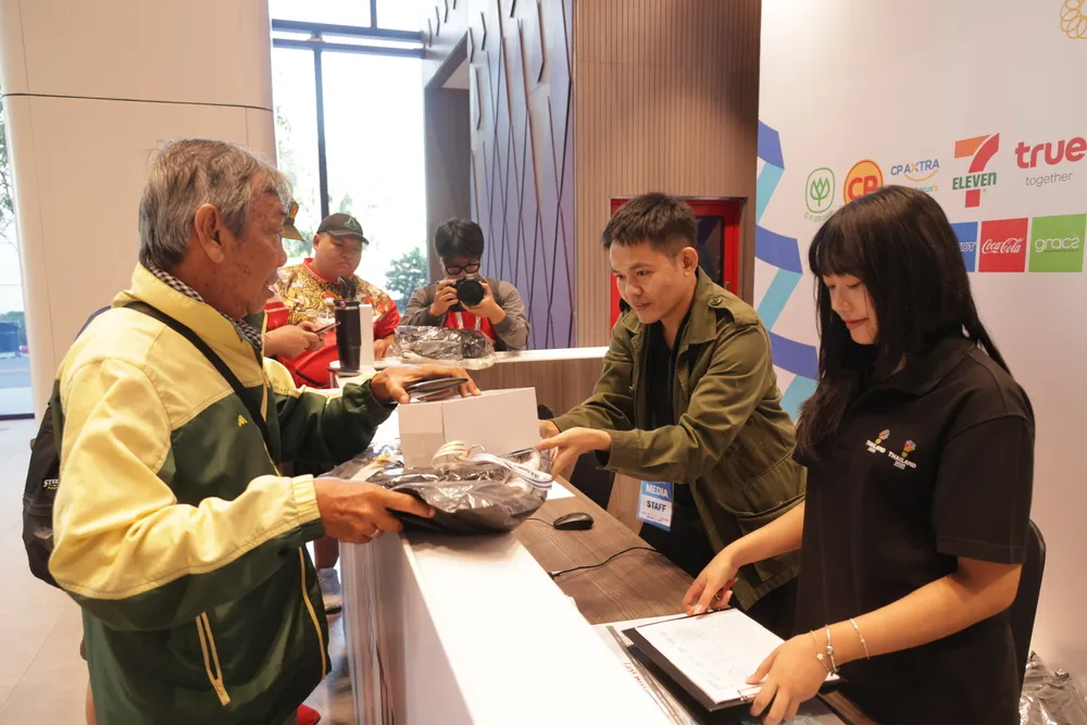 Đội ngũ tình nguyện viên của Ban tổ chức SEA Games 33 hỗ trợ nhà báo Dư Hải nhận thẻ tác nghiệp. ẢNH: DŨNG PHƯƠNG 
