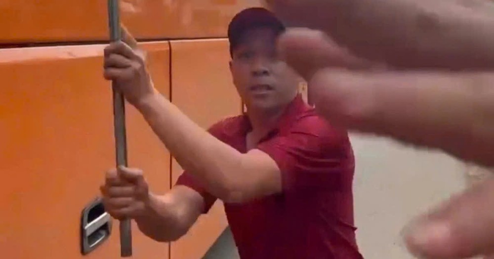 一名身穿客运公司制服的男子下车，拿出一根约1米长的铁棍，恐吓并企图殴打从后方驶来的摩托车驾驶者。