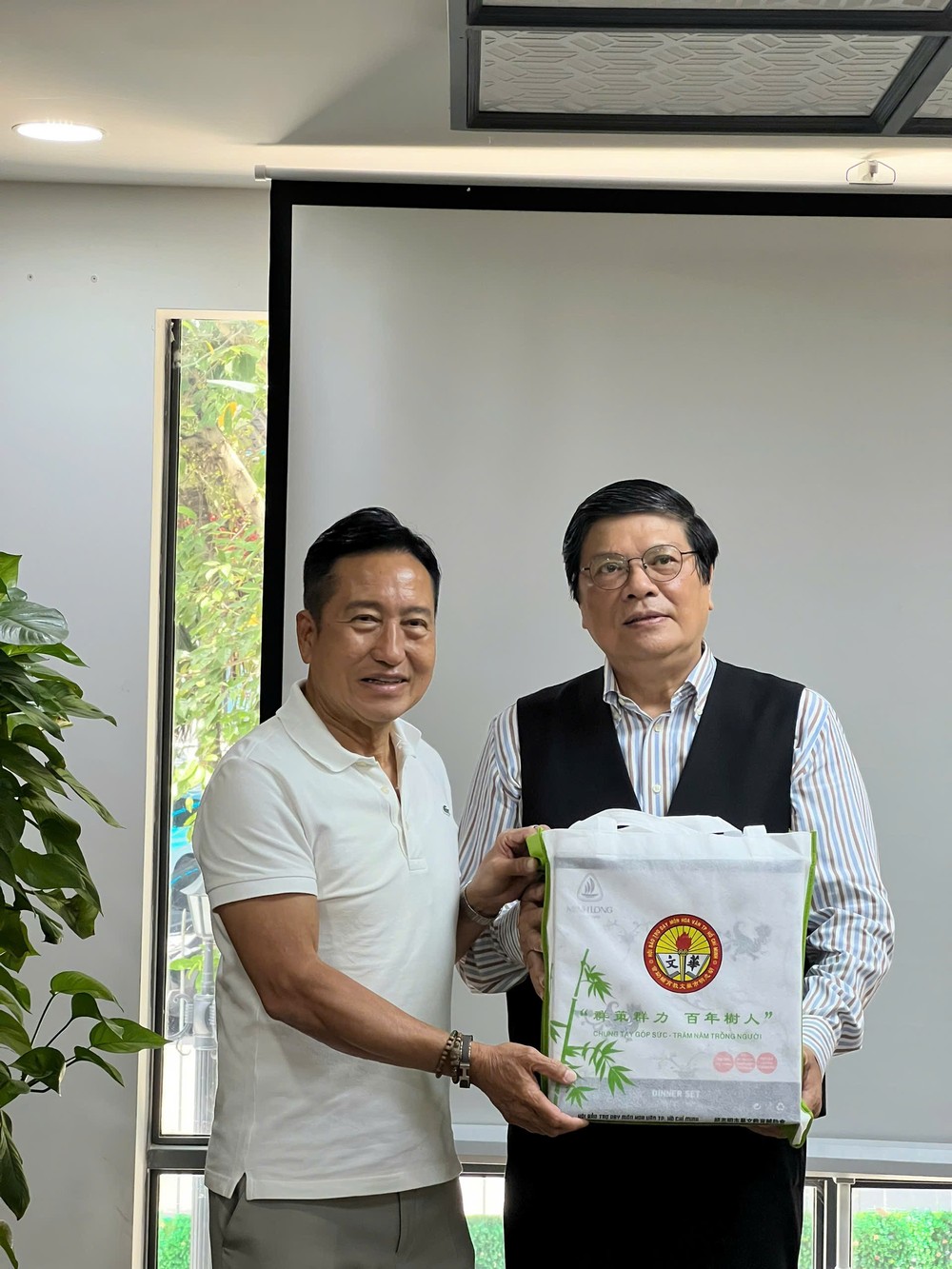 市华文教育辅助会主席古家寿向资深新闻工作者、城市规划研究学者陈友福进赠送礼物。 图：心雨