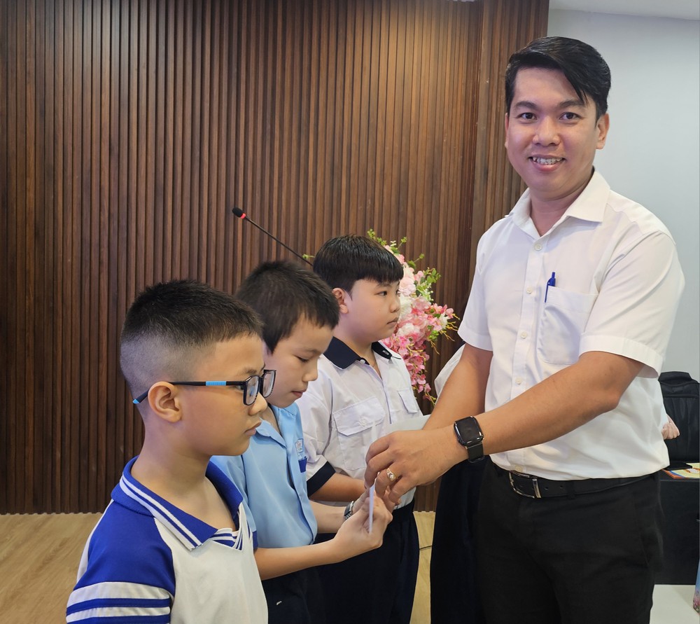 胡志明市越南祖国阵线委员会社会工作处副主任刘平龙向小学生颁发助学金。图：心雨