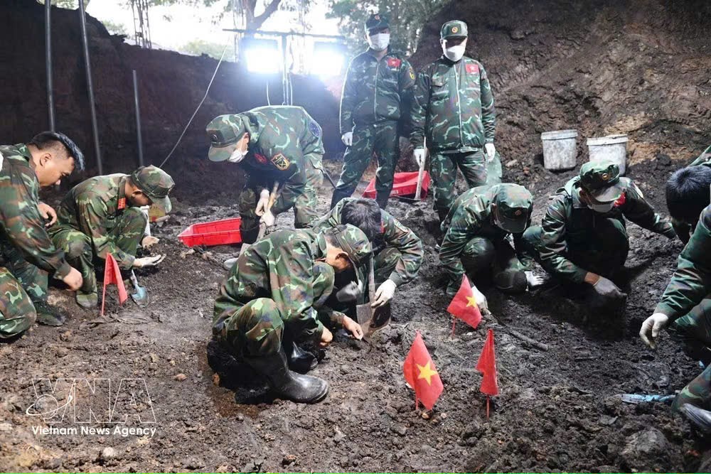 K74队干部、战士在刚发现的烈士集体墓区域展开烈士遗骸搜寻、归集工作。图自越通社