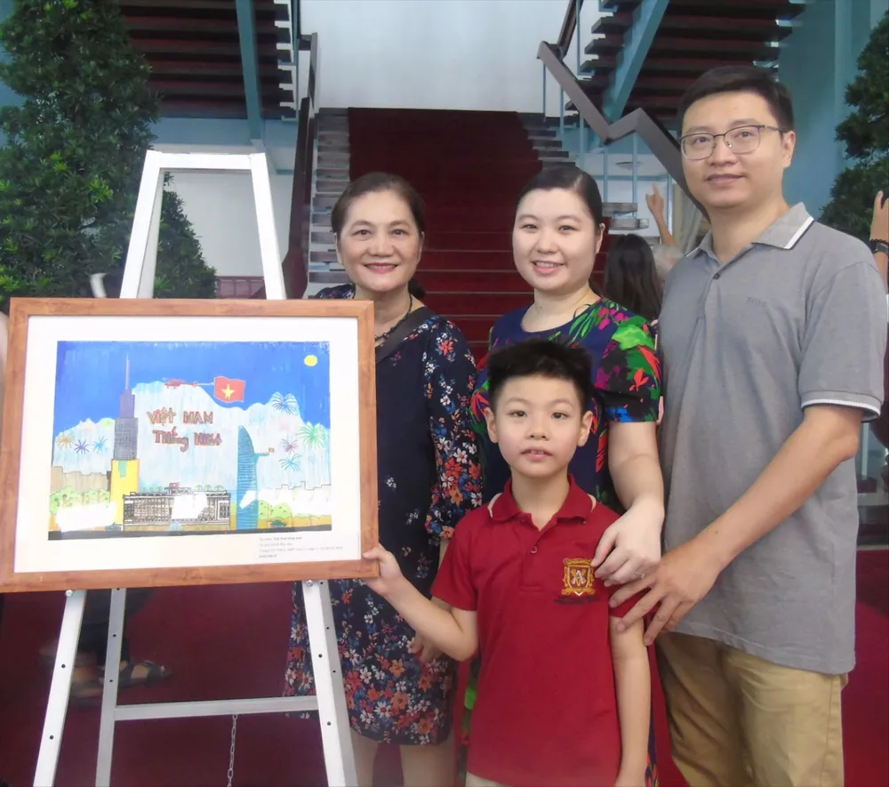 Gia đình và bé Phúc Huy chụp ảnh cùng bức tranh đạt giải Nhất.JPG