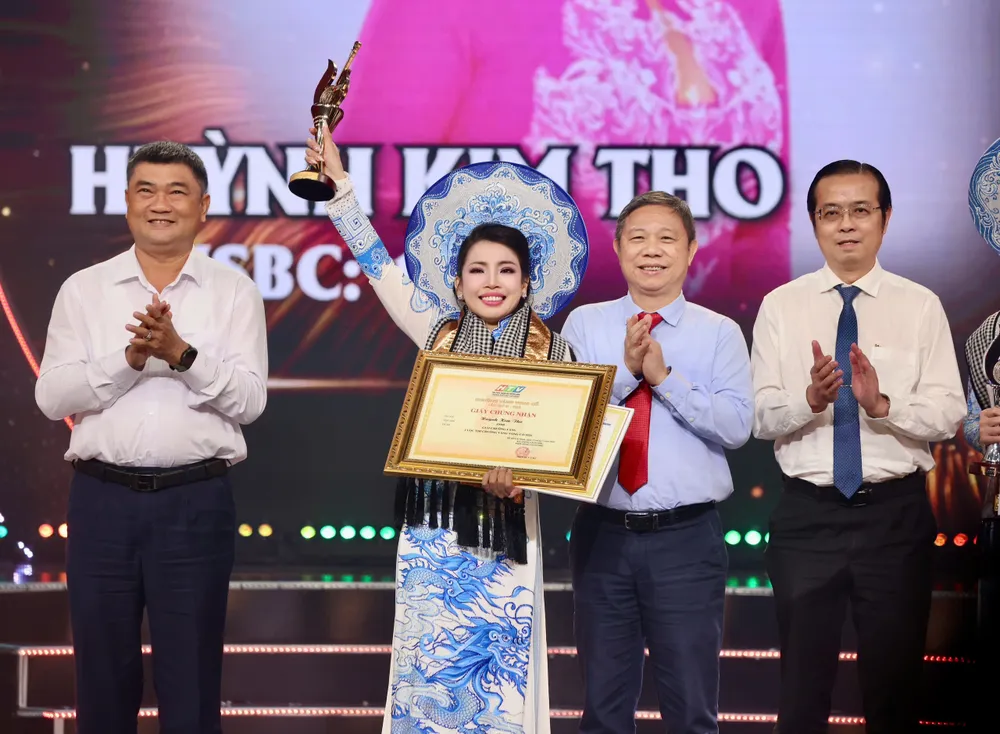 Các đồng chí: Trung tướng Lê Xuân Thế - Ủy viên Trung ương Đảng, Ủy viên Quân ủy Trung ương, Phó Bí thư Đảng ủy, Tư lệnh Quân khu 7; Dương Anh Đức - Ủy viên Ban Thường vụ Thành ủy, Trưởng Ban Tuyên giáo Thành ủy TPHCM; Lê Văn Minh, Thành ủy viên, Tổng Giám đốc Cơ quan Báo và Phát thanh, Truyền hình TPHCM trao giải Chuông Vàng vọng cổ 2026 cho thí sinh Huỳnh Kim Tho. Ảnh: HOÀNG TRIỀU