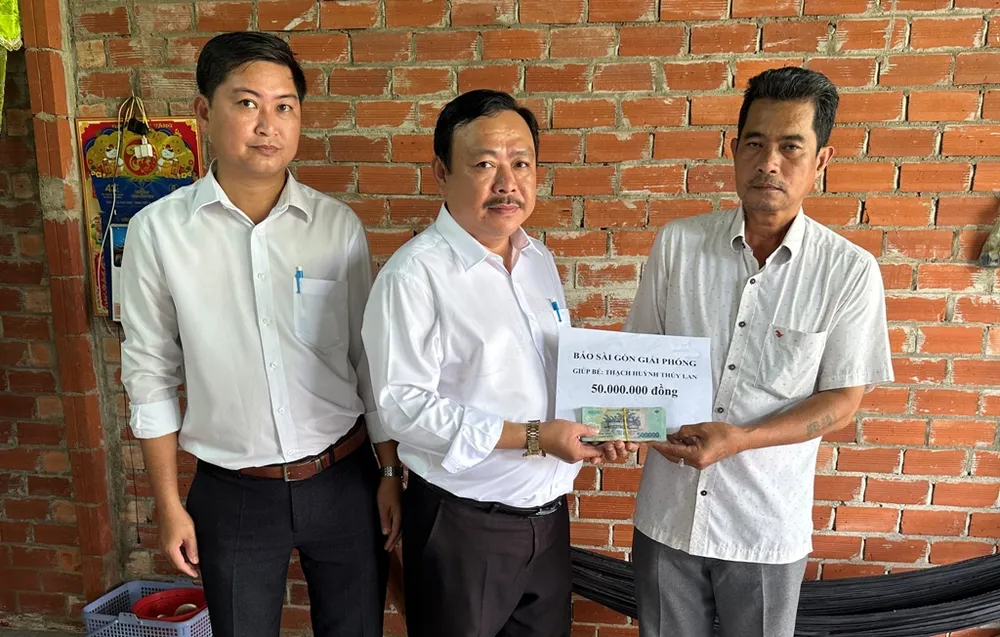 Anh Thạch Hoành Na (bìa phải) nhận 50 triệu đồng hỗ trợ đợt 1 từ Báo SGGP