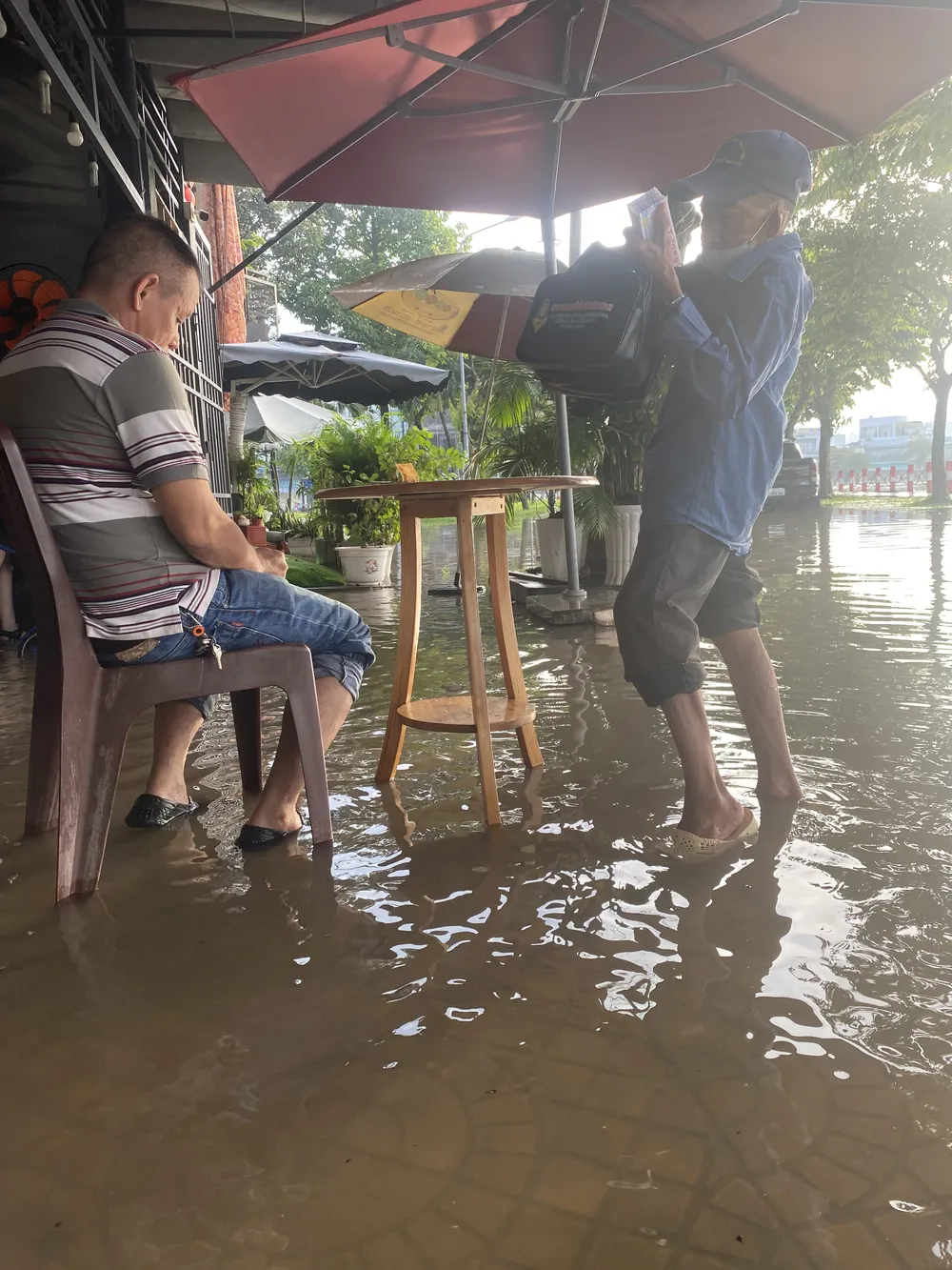 Một người bán vé số tranh thủ lội nước bán cho khách ở hồ Xáng Thổi sáng 1-10