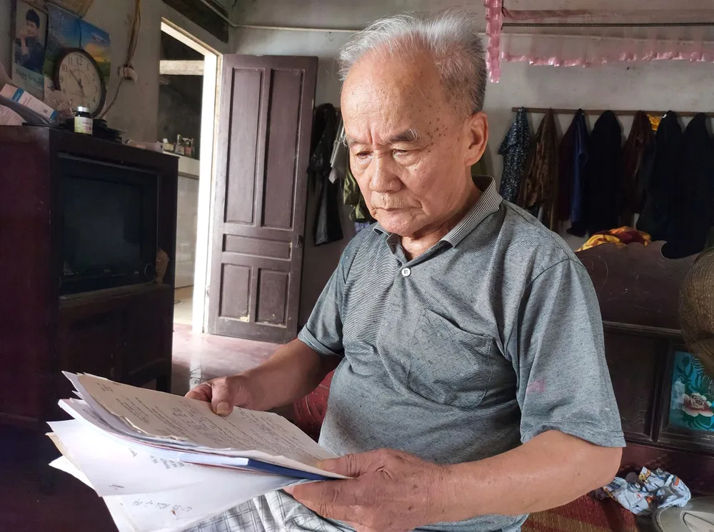 Ông Vương Khả Khai bên tập giấy tờ ghi chép  tìm kiếm phần mộ liệt sĩ