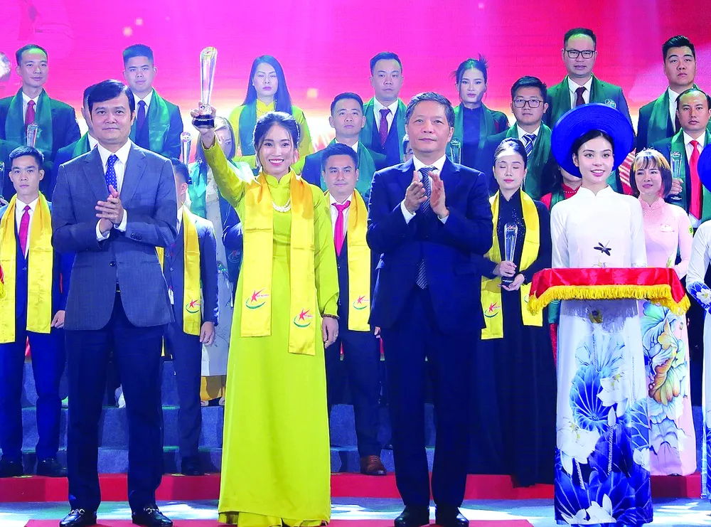 Trưởng Ban Kinh tế Trung ương Trần Tuấn Anh (phải) cùng Bí thư thứ nhất Trung ương Đoàn Bùi Quang Huy trao khăn và biểu trưng cho Chủ tịch kiêm Tổng Giám đốc Công ty Cổ phần Zoro Aya Nguyễn Thị Hạnh được vinh danh tốp 10 doanh nhân trẻ khởi nghiệp xuất sắc Ảnh: TTXVN