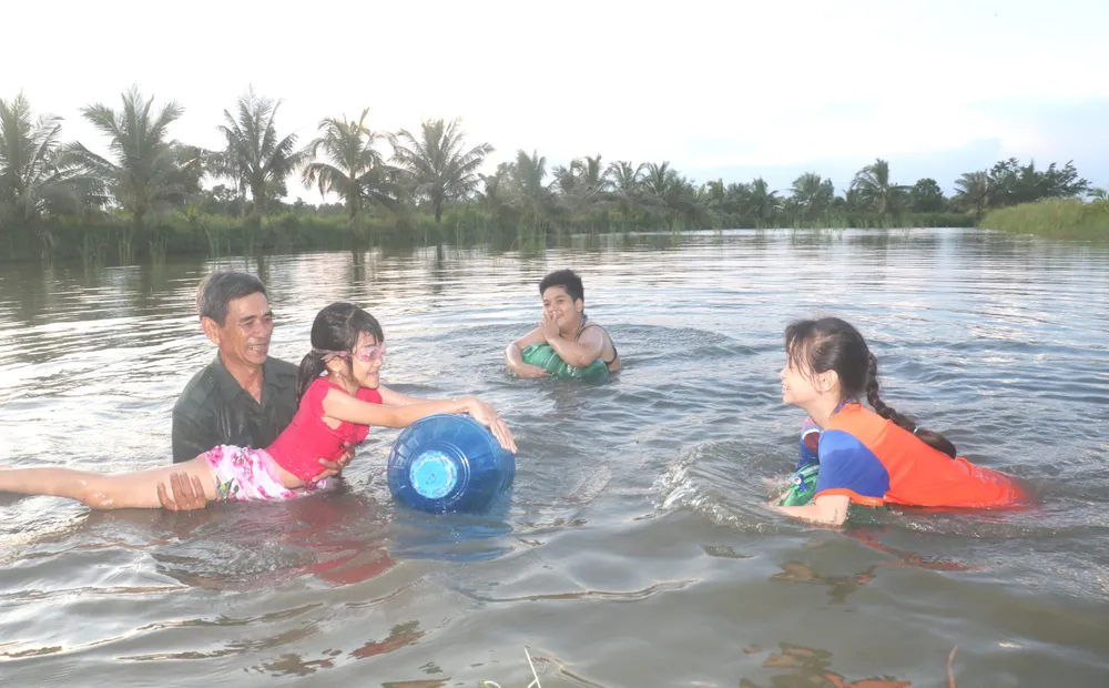 Các em học sinh tập bơi trong vuông tôm, để trang bị kỹ năng phòng chống đuối nước tại phường 9, TP Cà Mau, tỉnh Cà Mau. Ảnh: TẤN THÁI