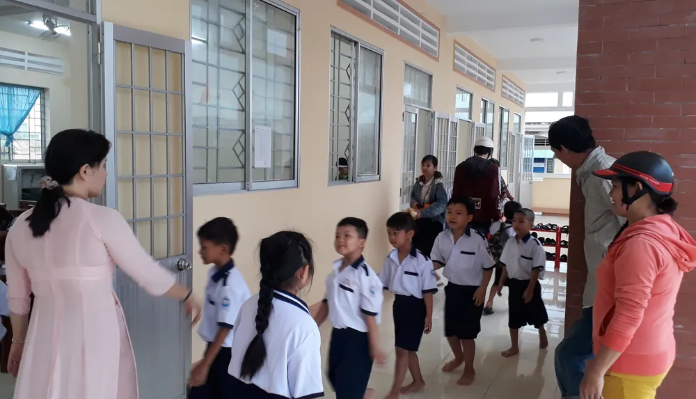 Giáo viên Trường Tiểu học Văn Lang (phường An Xuyên, tỉnh Cà Mau) hướng dẫn học sinh vào lớp học. Ảnh: TẤN THÁI