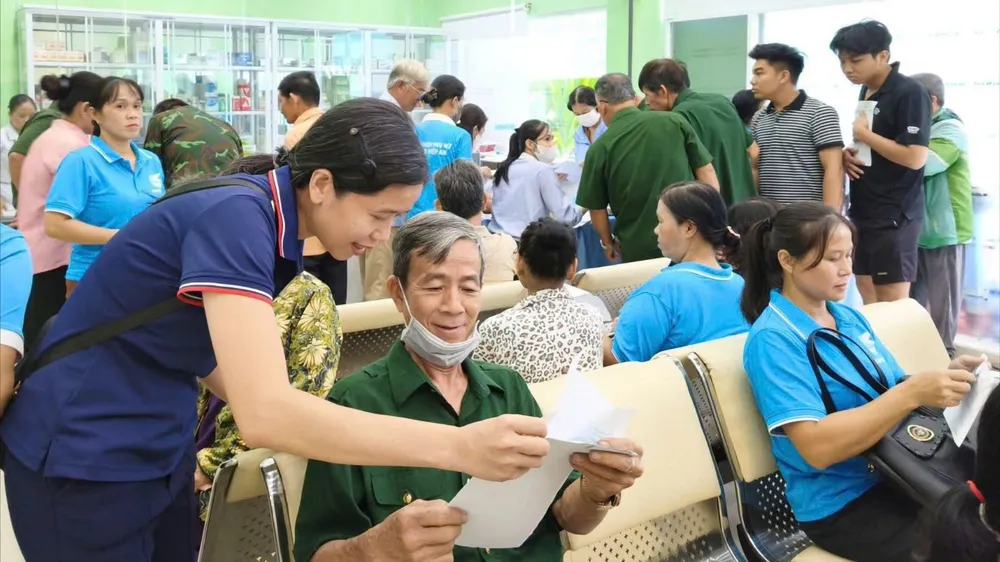 Lực lượng tình nguyện của phường Chánh Hiệp hỗ trợ người lớn tuổi thuộc diện gia đình chính sách đi khám sức khỏe. Ảnh: THẢO NGUYỄN