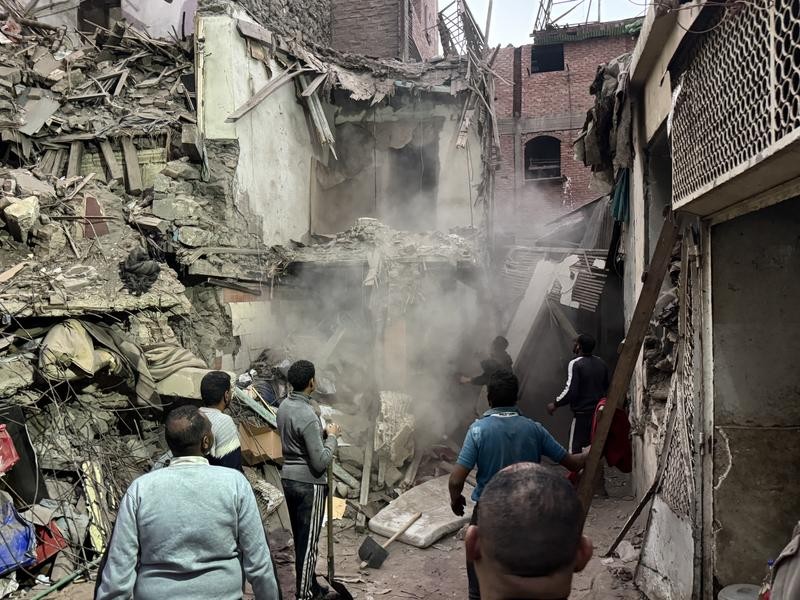 12月25日，救援人员在埃及吉萨省因巴拜区一处倒塌的房屋废墟工作。