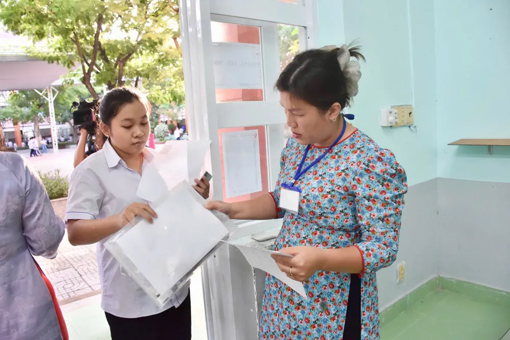 Giám thị kiểm tra vật dụng thí sinh mang vào phòng thi tại điểm thi THCS Trần Phú (phường Tam Thắng, TPHCM). Ảnh: KHÁNH CHI