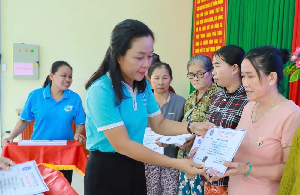 Đại diện Hội LHPN Thành phố Hồ Chí Minh trao thẻ bảo hiểm y tế cho hội viên, phụ nữ có hoàn cảnh khó khăn. Ảnh: Q.V