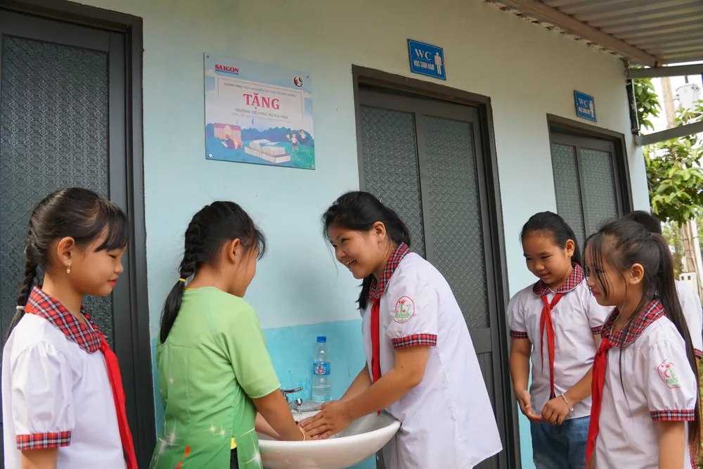 Các em học sinh điểm trường Cầu Sập (huyện Bù Gia Mập, tỉnh Bình Phước) vui mừng bên nhà vệ sinh khang trang do Báo SGGP xây tặng.JPG