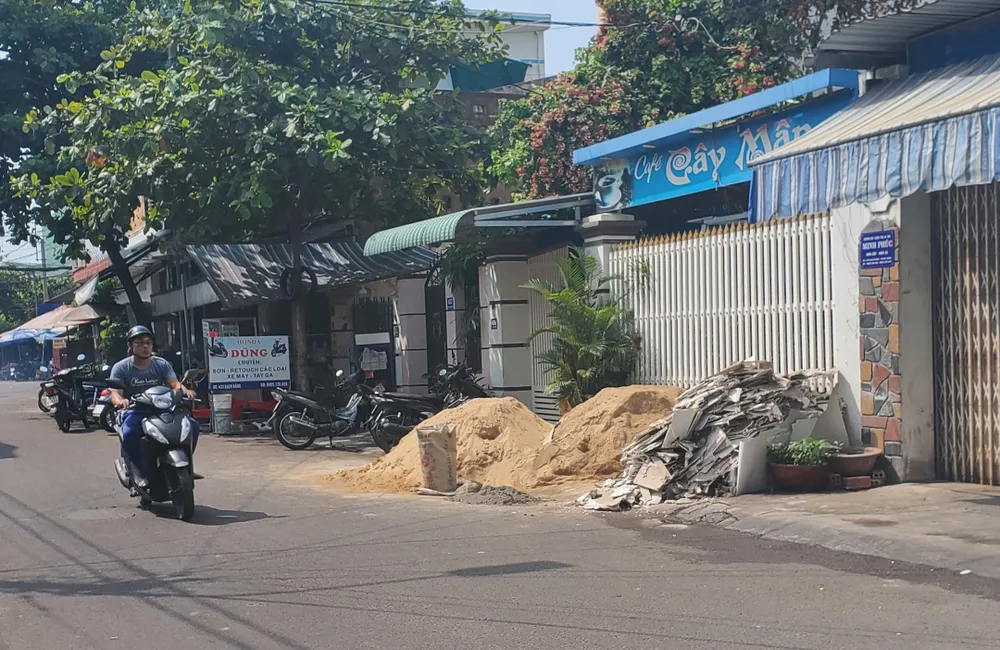 Bãi vật liệu nằm tràn trên đường Bạch Đằng (TP Quy Nhơn) vào sáng 27-4. Bên cạnh đó là hàng quán chiếm vỉa hè, xe máy dựng tràn xuống lòng đường.