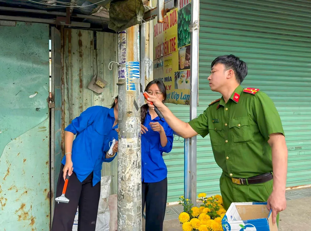 Cán bộ, chiến sĩ Công an xã Tân Vĩnh Lộc, TPHCM cùng đoàn viên thanh niên các đơn vị ra quân xóa quảng cáo sai quy định.jpg
