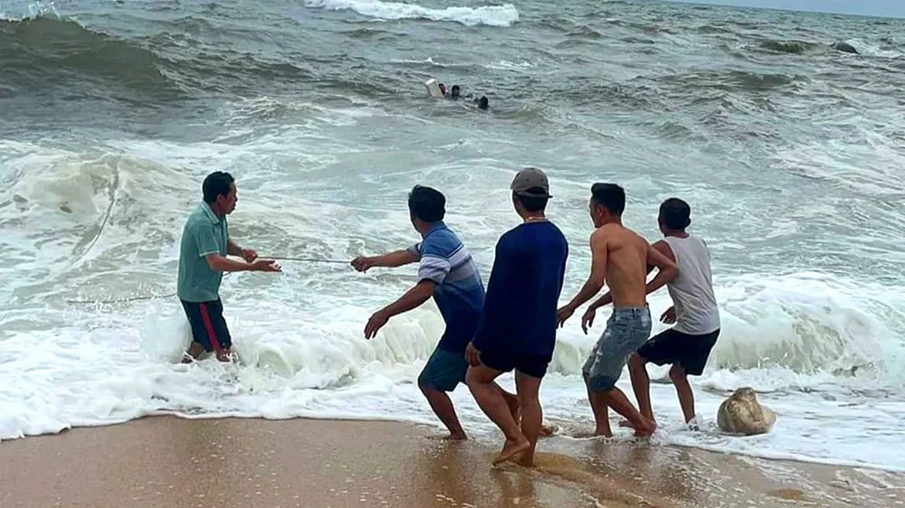 Người dân ở xã Kỳ Xuân, huyện Kỳ Anh, tỉnh Hà Tĩnh dùng dây thừng đưa 3 ngư dân gặp nạn vào bờ