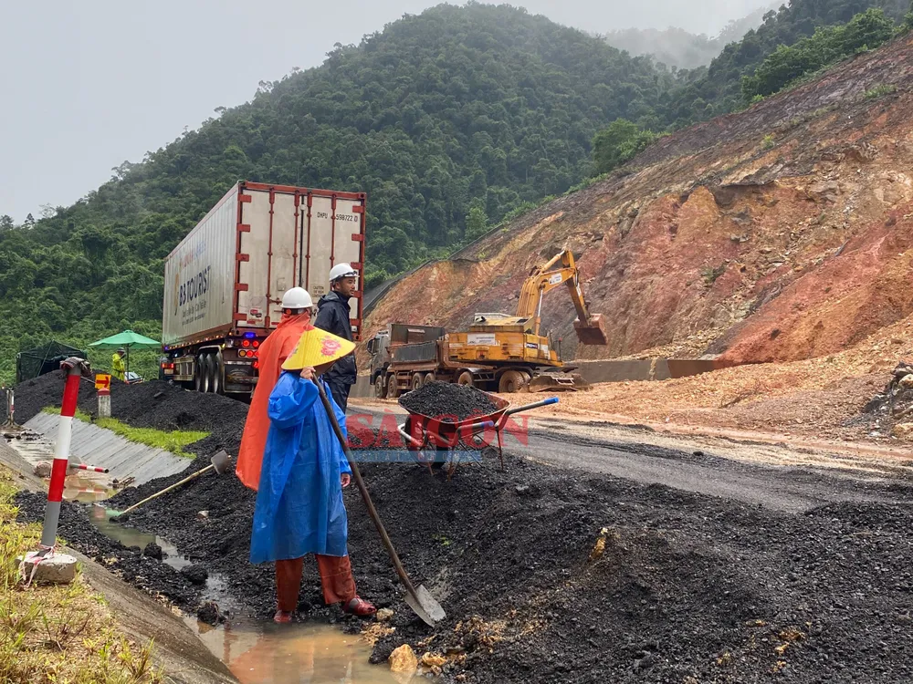 Tại hiện trường, hàng chục công nhân dầm mưa, dọn dẹp đất đá đảm bảo an toàn cho phương tiện lưu thông