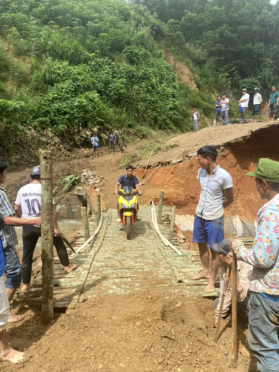 Người dân xã Ba Nang, huyện Đakrông, tỉnh Quảng Trị cùng Bộ đội Biên phòng dựng tạm cầu tre qua đoạn đường tuần tra biên giới bị lũ gây sạt lở, chia cắt