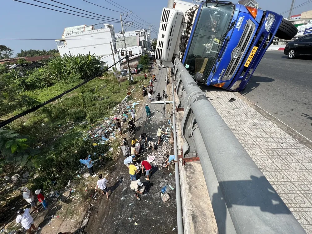 Xe tải đông lạnh va quẹt vào khoảng 20m lan can và bị lật nằm đè lên trên lan can cầu