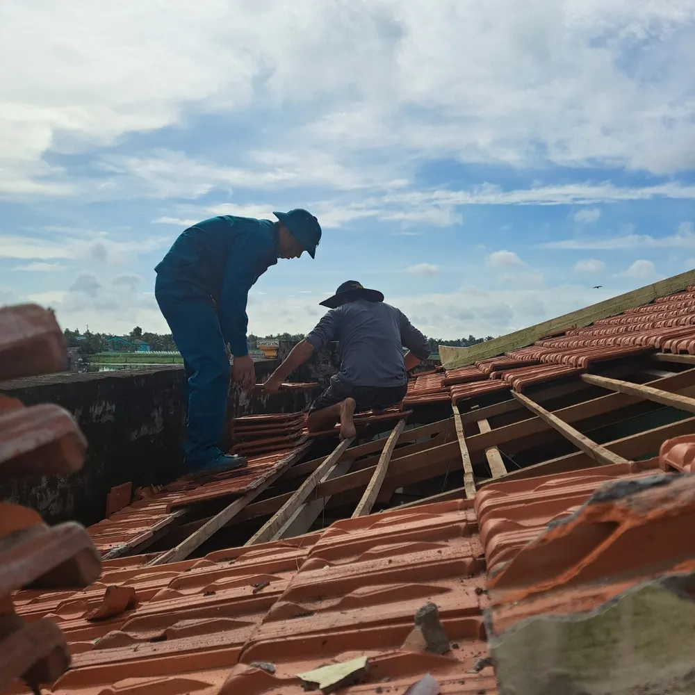 Lực lượng dân quân hỗ trợ người dân sửa chữa lại nhà bị tốc mái