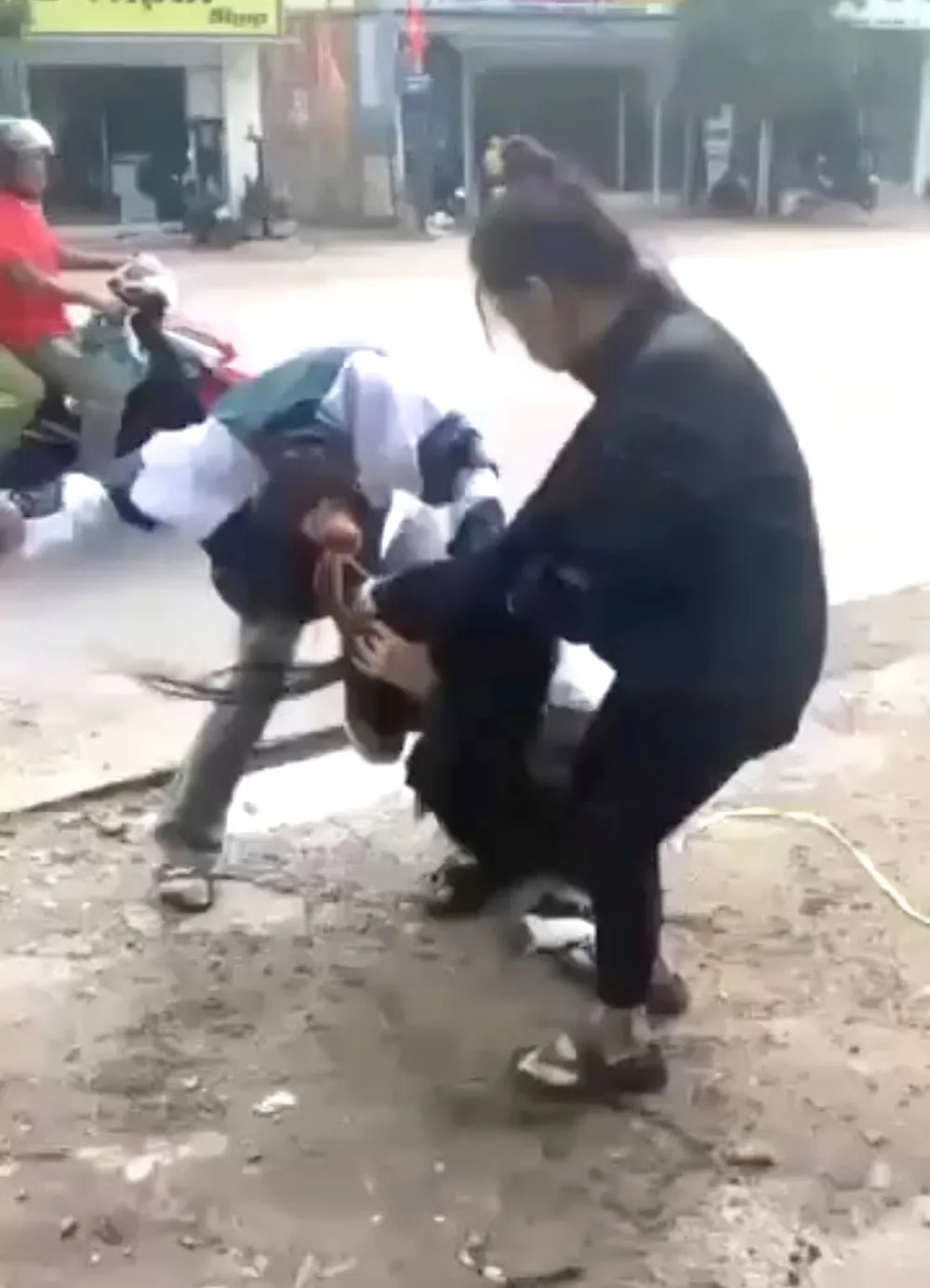 Hai người lạ hành hung em L. trước cổng trường. Ảnh cắt từ clip