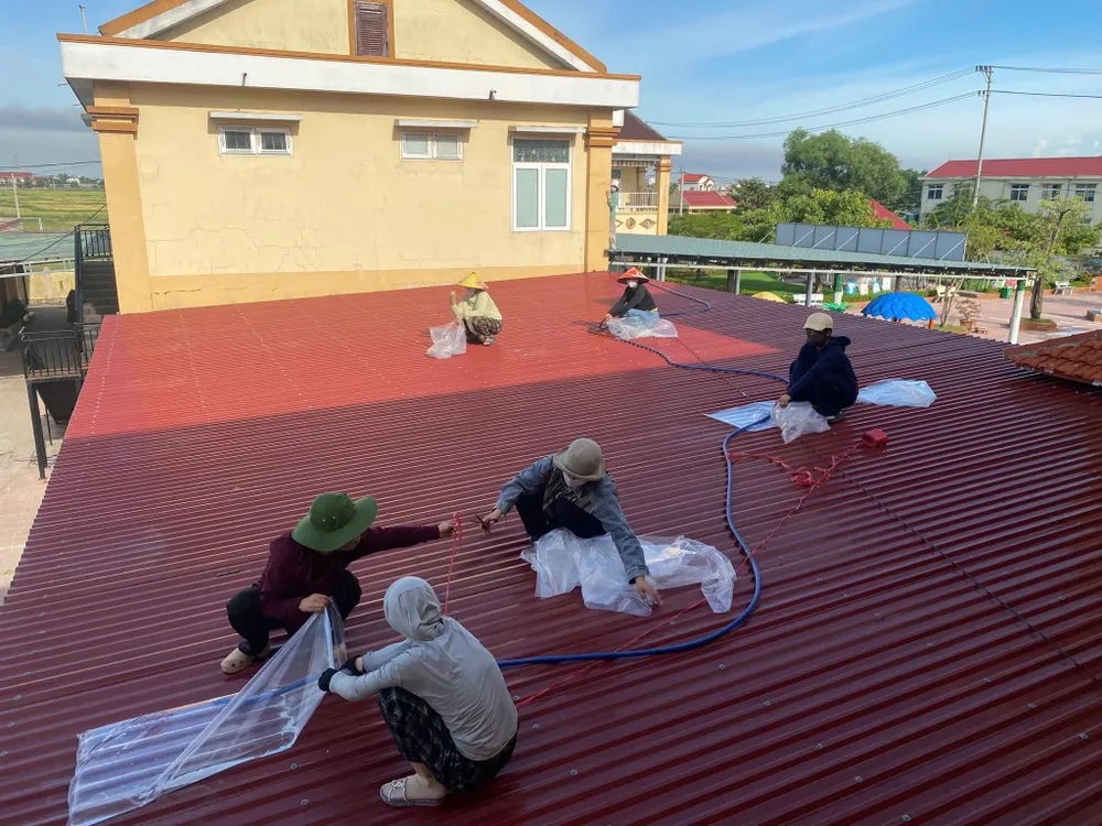 Nhân viên Trường mầm non Quảng Phú, xã Phú Trạch dùng nước thay bao cát che chắn mái tôn