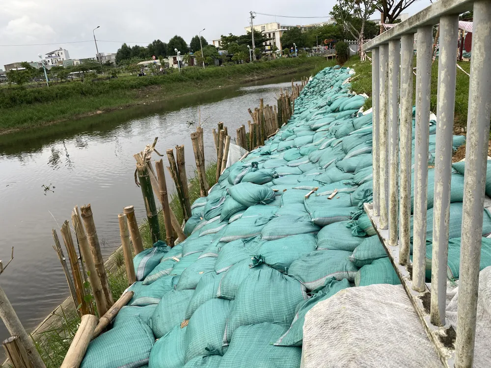 Theo ghi nhận, đoạn bờ kè bị sạt lở kéo dài hàng chục mét, nhiều chỗ bị sụt lún sâu phải được gia cố tạm thời bằng bao cát và cọc tre