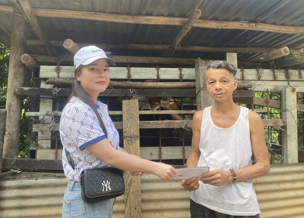 Đại diện nhà hảo tâm trao tiền hỗ trợ đến ông A lăng Vinh (cha của A lăng Đức, mắc bệnh tâm thần)