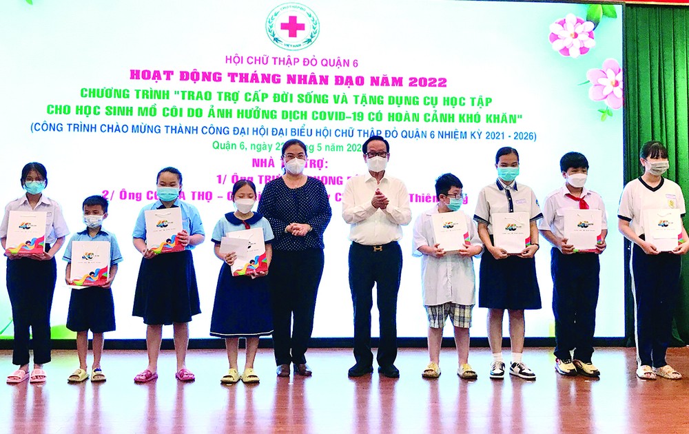 　　第六郡人委會主席黎氏青草與張豐裕先生向父母雙亡的孤兒派發禮物。