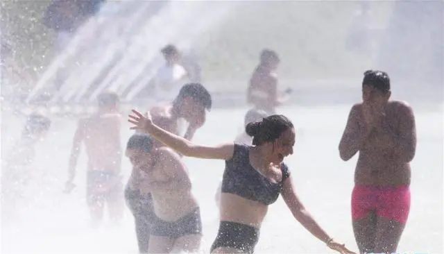 人们在喷泉里消暑纳凉。(新华社)