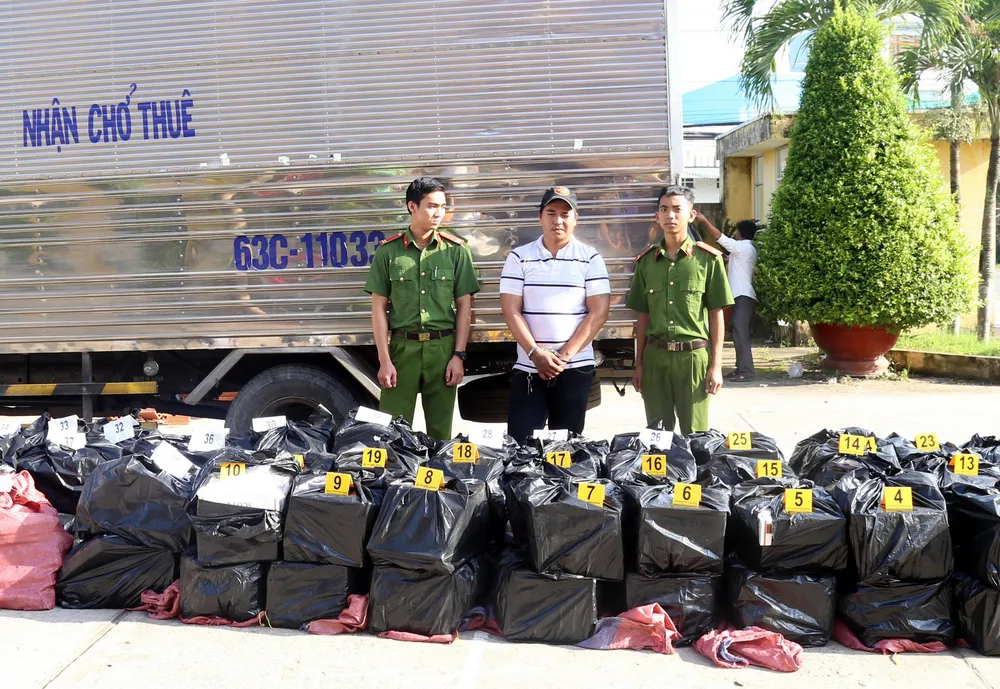 Đối tượng Thiện cùng tang vật hơn 20.000 bao thuốc lá lậu. Ảnh: TUẤN QUANG