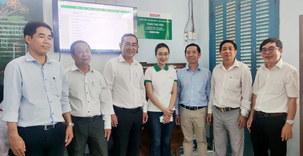 Ban tổ chức cùng gỡ bảng trao tặng thư viện Trường THCS Tân Xuân. Ảnh: VIỆT NGA