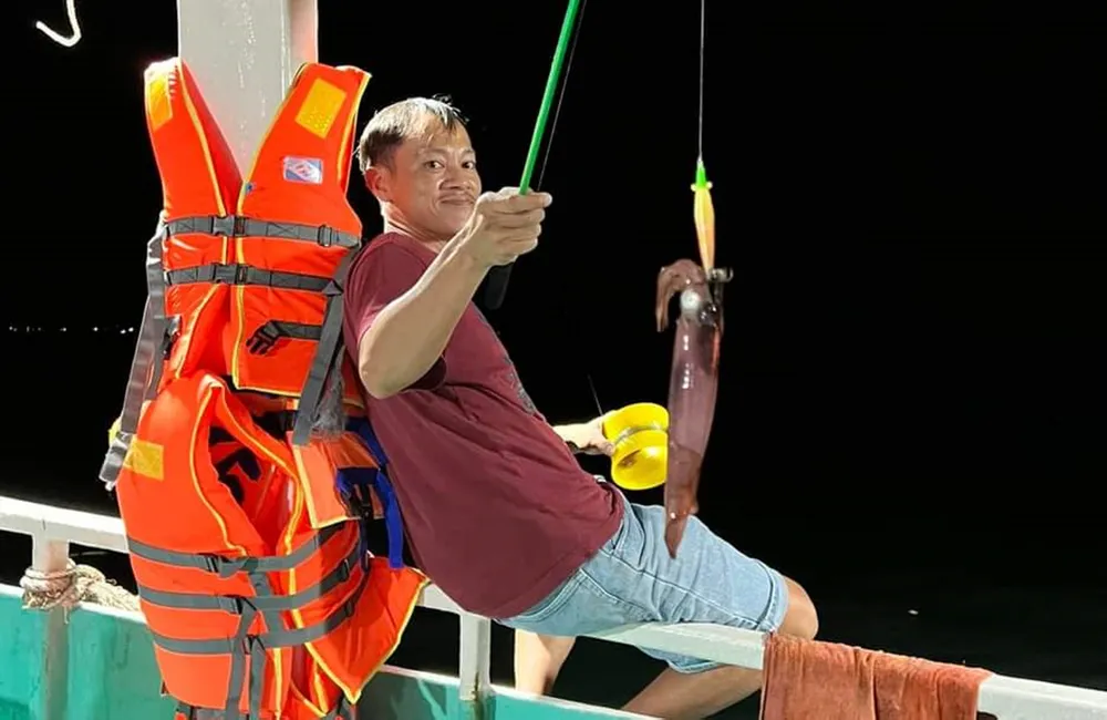 Du khách thích thú khi tự tay mình câu được mực từ biển lên. Ảnh: QUỐC BÌNH