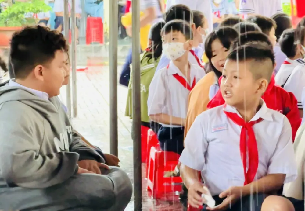 Học sinh vùng sâu huyện Vĩnh Thuận (tỉnh Kiên Giang) vui vẻ gặp lại bạn dưới mái bạt che mưa. Ảnh: QUỐC BÌNH