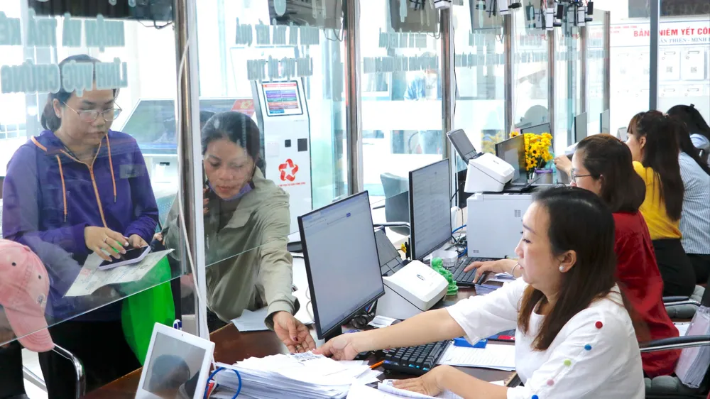 Công chức Trung tâm Phục vụ hành chính công xã Bà Điểm (một trong các xã đủ điều kiện thành lập đơn vị hành chính đô thị) hướng dẫn người dân thực hiện thủ tục hành chính. Ảnh: NGÔ BÌNH