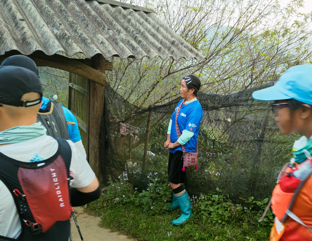 Một phụ nữ đồng bào nhìn những vận động viên đi qua